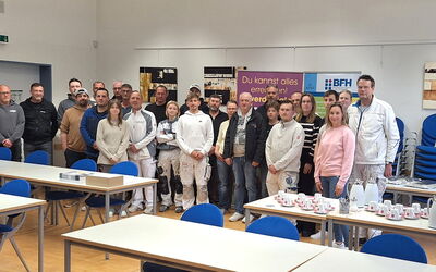 Teilnehmende stehen in Zweiherreihe im Konrad-Seibel-Raum und blicken lächelnd in die Kamera – gemeinsames Seminar zur Lehmtapete.